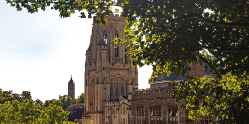 The University of Bristol Wills Memorial Building tower seen through the green leaves of surrounding trees.